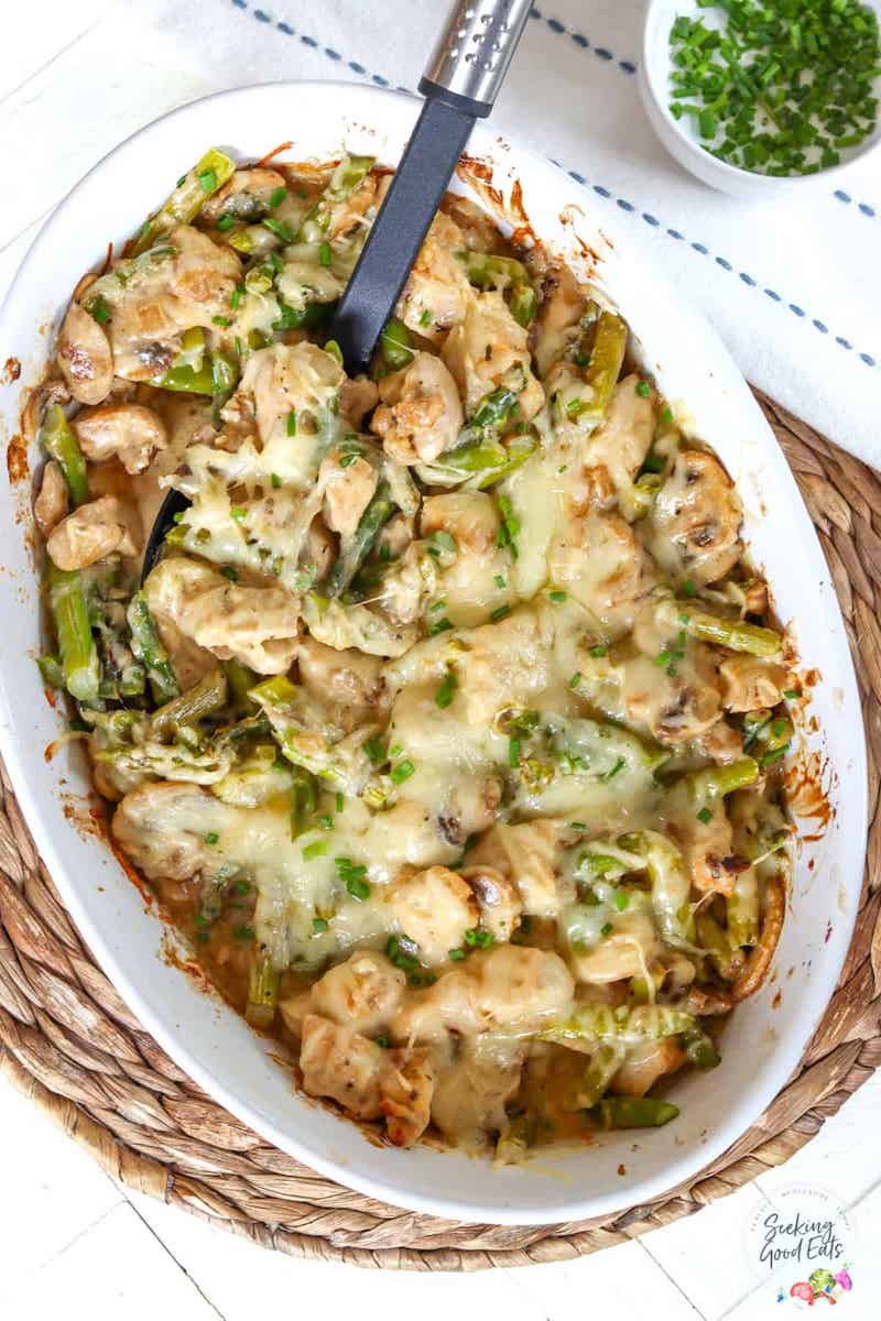 An image showcasing a Low Carb Keto Creamy Chicken Bake Recipe - a mouthwatering casserole dish topped with golden, melted cheese, full of tender chicken pieces smothered in a rich and creamy sauce, garnished with fresh herbs.