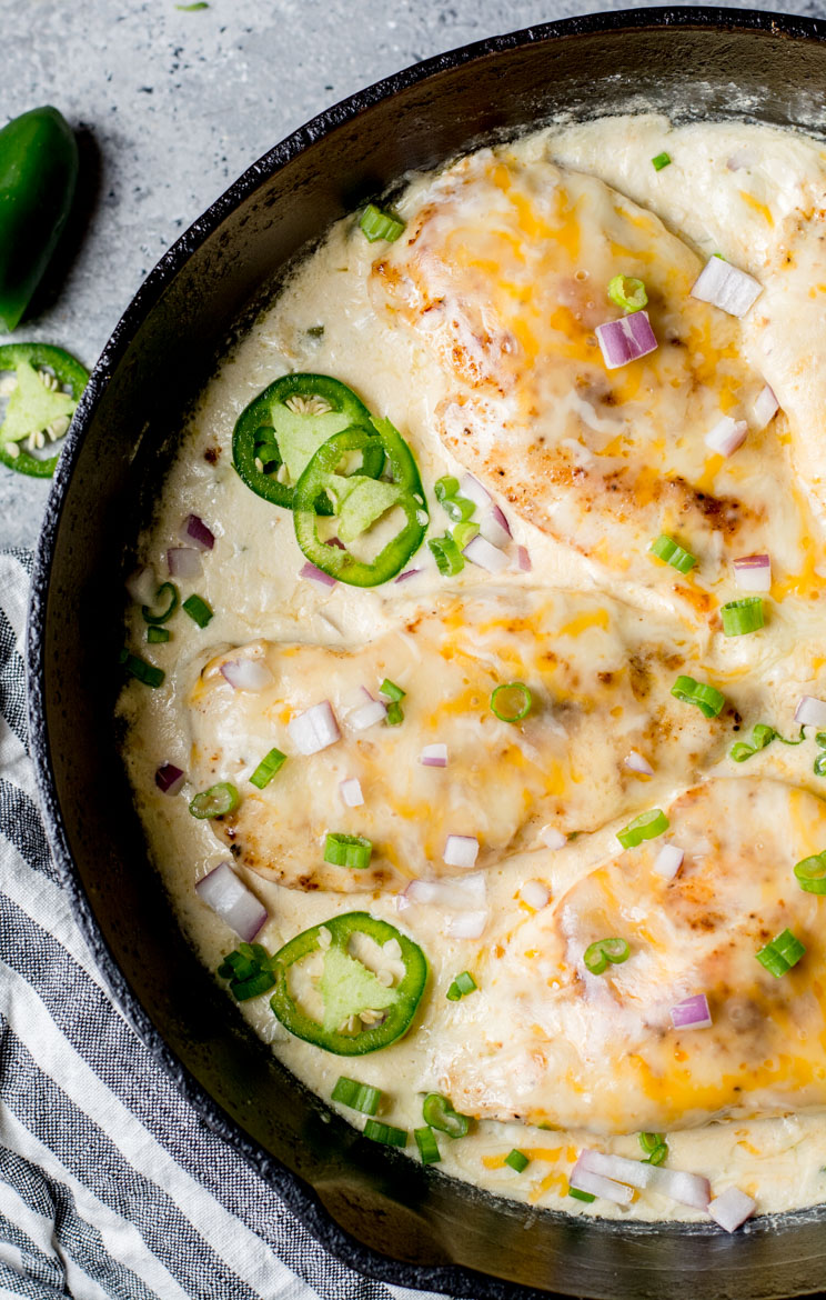 An image displaying a One Pan Keto Cheesy Jalapeño Chicken dish - a tantalizing entree composed of tender chicken breast cooked to perfection and smothered in a creamy sauce with cream cheese, cheddar cheese, and spicy jalapeño. Other ingredients like onion, butter, and garlic enhance the dish's savory allure. It's served hot from the skillet, capturing the simplicity of its 16-minute preparation. The overall look of this dish signals a perfect low-carb dinner or an easy keto meal prep solution.