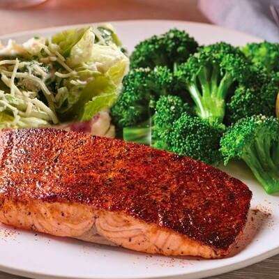 Image featuring Applebee's Blackened Cajun Salmon, rich in healthy fats and omega-3s, paired with either a fresh salad or steamed broccoli, epitomizing a tasty yet health-conscious, keto-friendly meal option.
